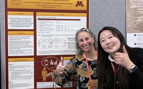 A professor and graduate student in front of a research poster.